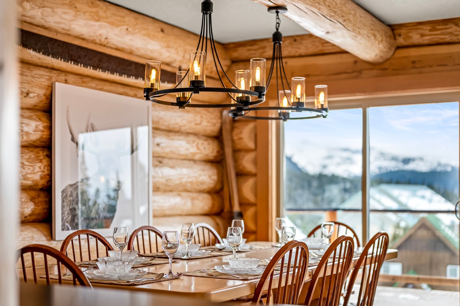 Dining room in a Mount Washington log home, set for a meal with snowy peaks outside